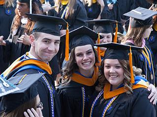 three graduates smiling at commencement